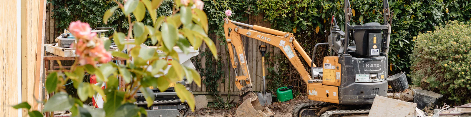 A mini excavator digging a foundation trench in a garden
