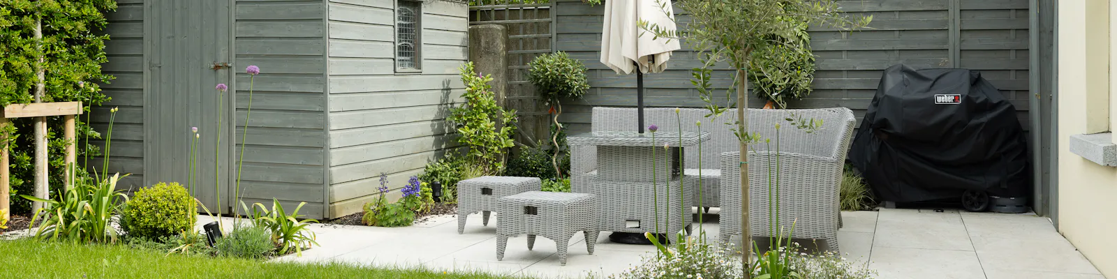 A finished stone patio with a table, chairs and a parasol